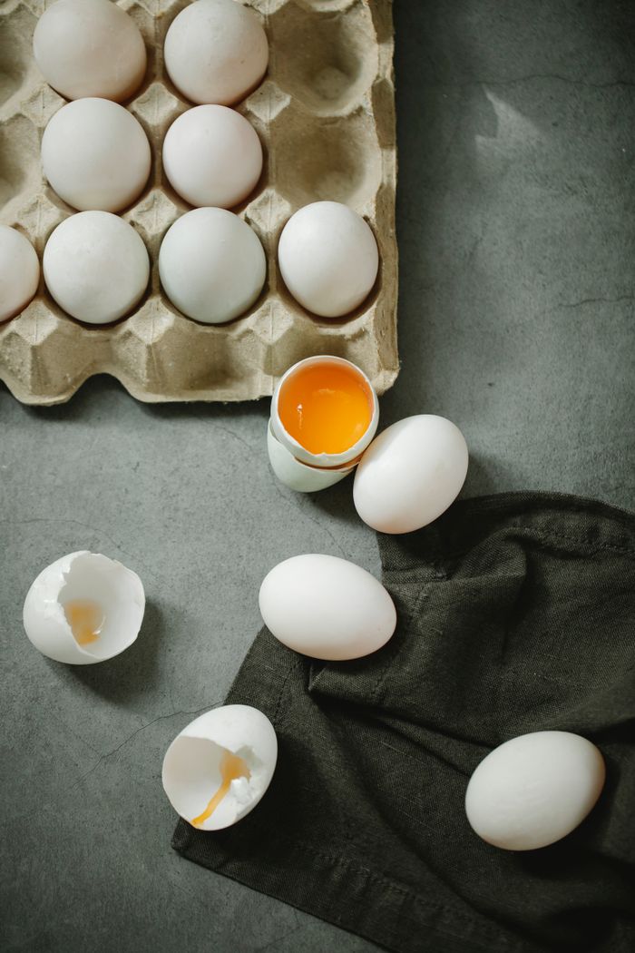 About Top view composition of raw organic eggs placed in egg carton and scattered on dark table in kitchen